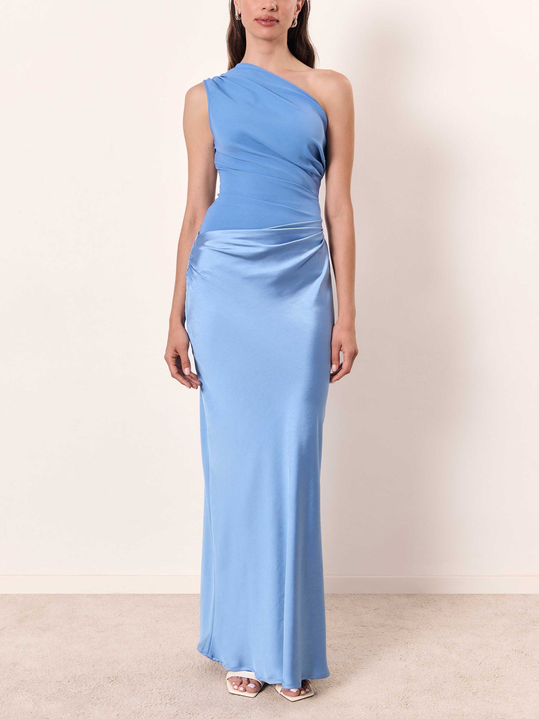 Woman wearing a light blue one-shoulder gown against a plain background