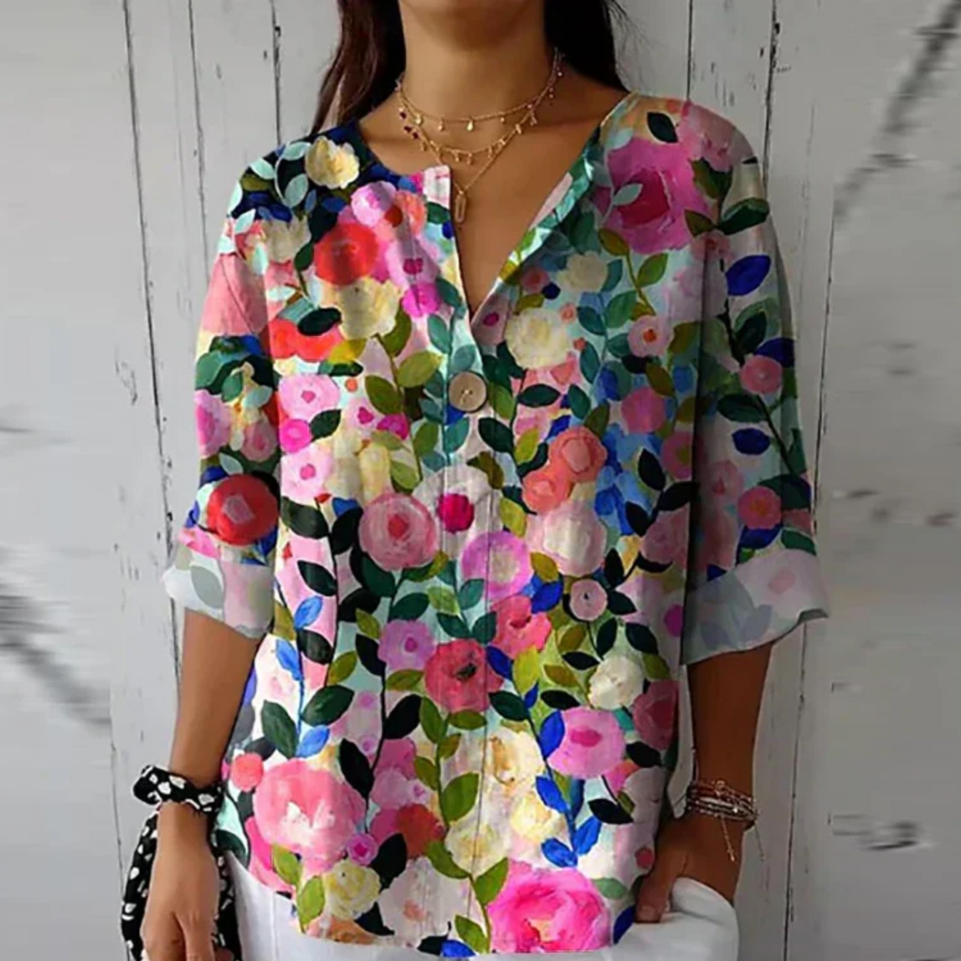 Person wearing a colorful floral shirt against a white wooden background