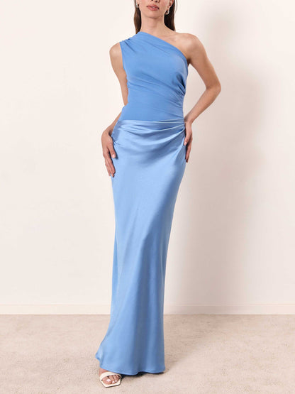 Woman wearing a light blue one-shoulder gown against a plain background