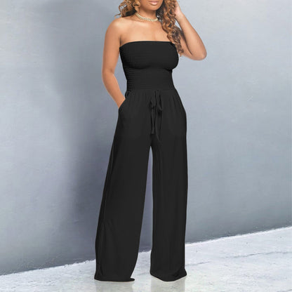 Woman wearing a black strapless jumpsuit against a gray background