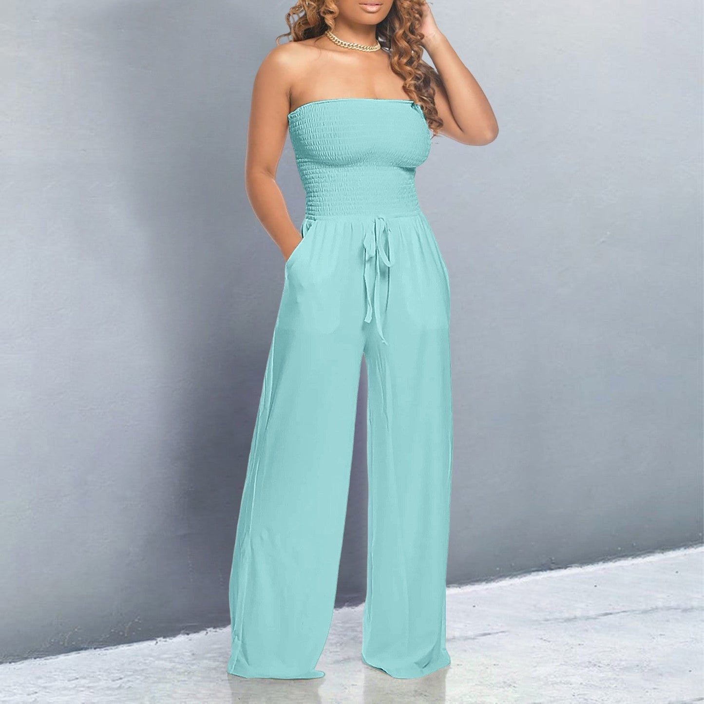 Woman wearing a light blue strapless jumpsuit against a gray background