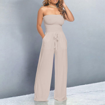 Woman wearing a beige strapless jumpsuit against a gray background