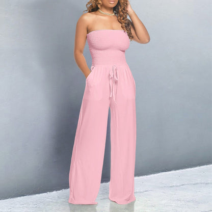 Woman wearing a pink strapless jumpsuit against a gray background