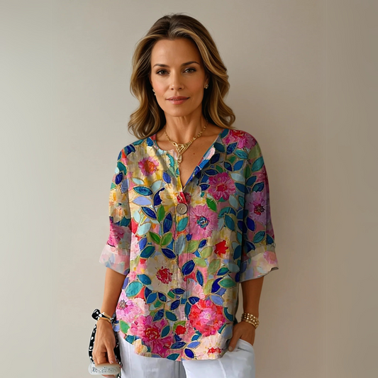 Woman wearing a colorful floral blouse against a plain background